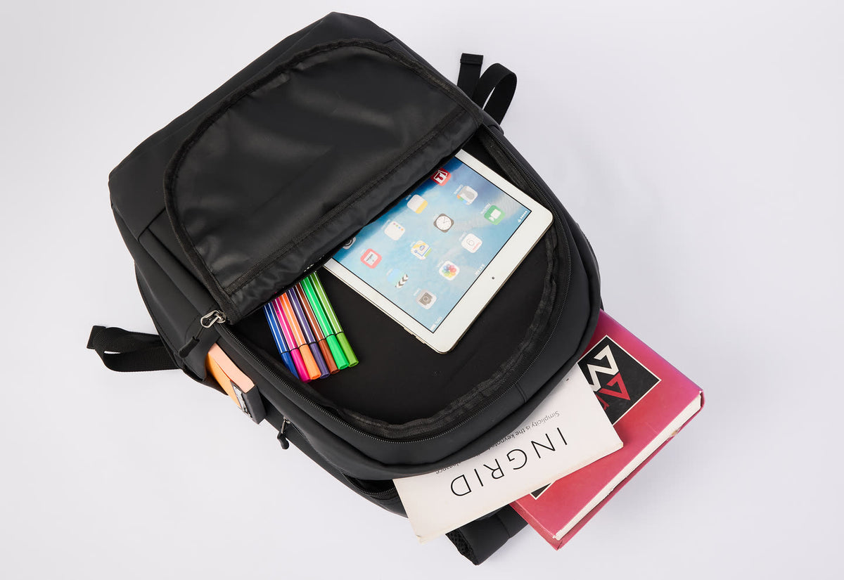 GA Backpack open on a white background holding a tablet, pens and books