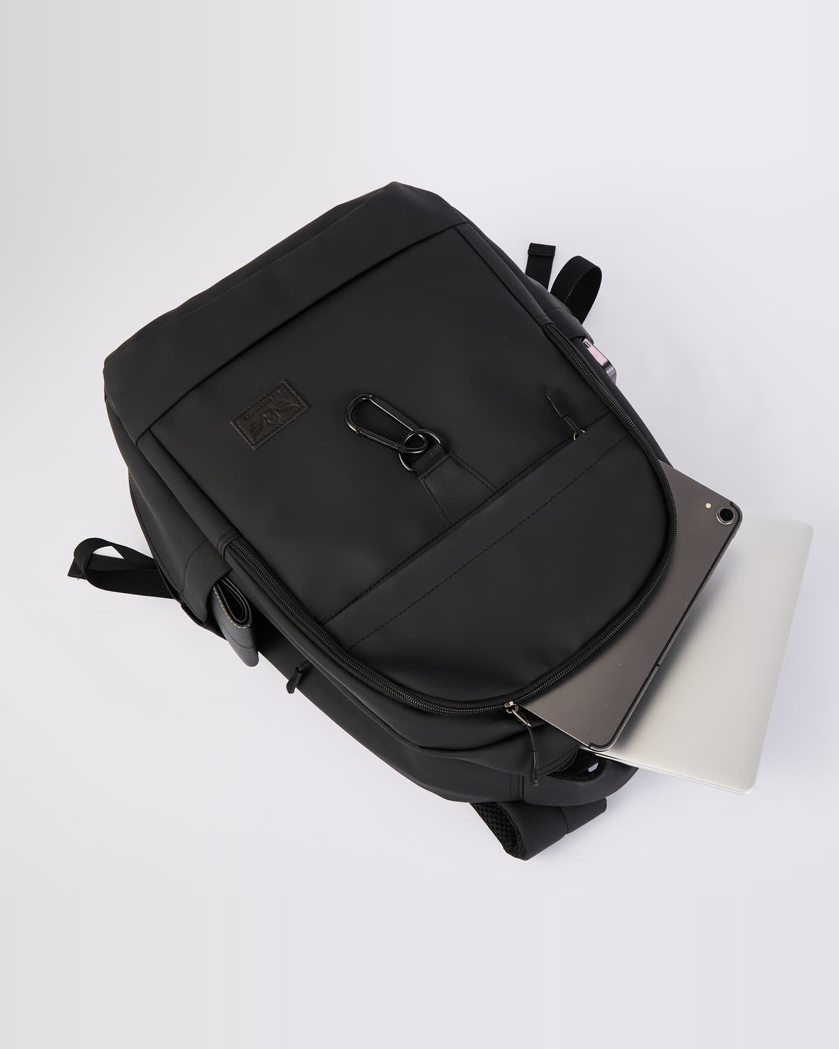 GA Backpack lying flat with a laptop partly removed from the rear sleeve